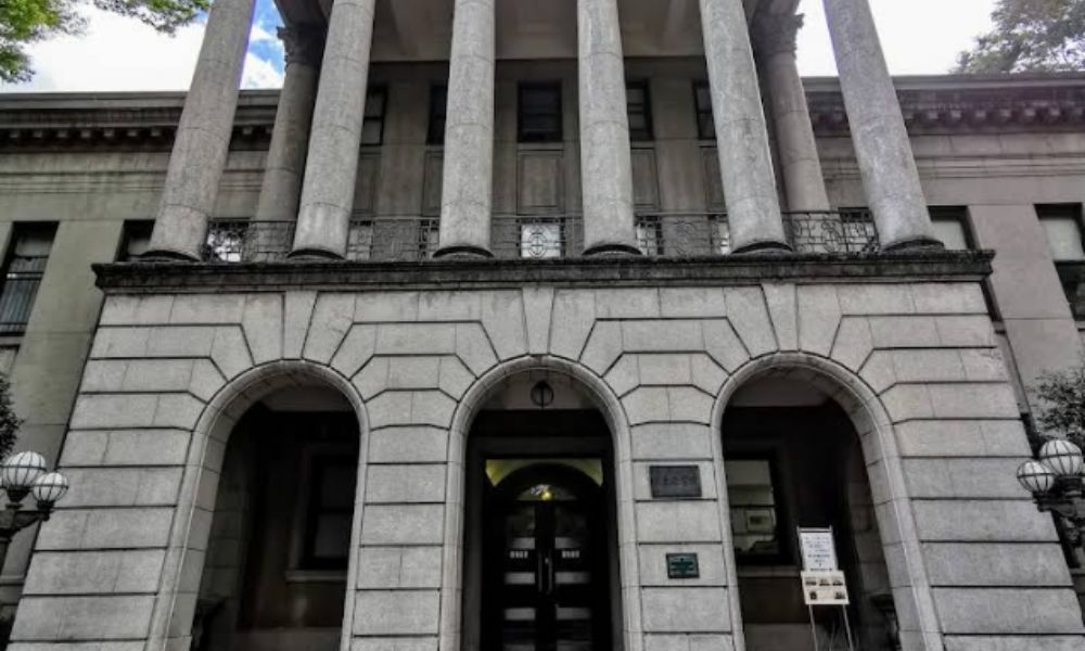 青山学院大学青山キャンパスの本館外観。大きな円柱とアーチ型の入口を持つクラシックな石造りの建物