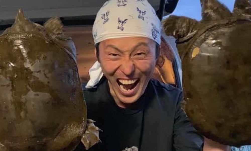 天然食材ハンター「野人」谷田圭太が両手に巨大なスッポンを持って満面の笑みを浮かべる写真