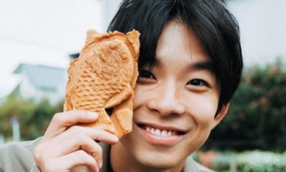 仲野太賀がたい焼きを顔の横に持って笑顔で写るポートレート写真