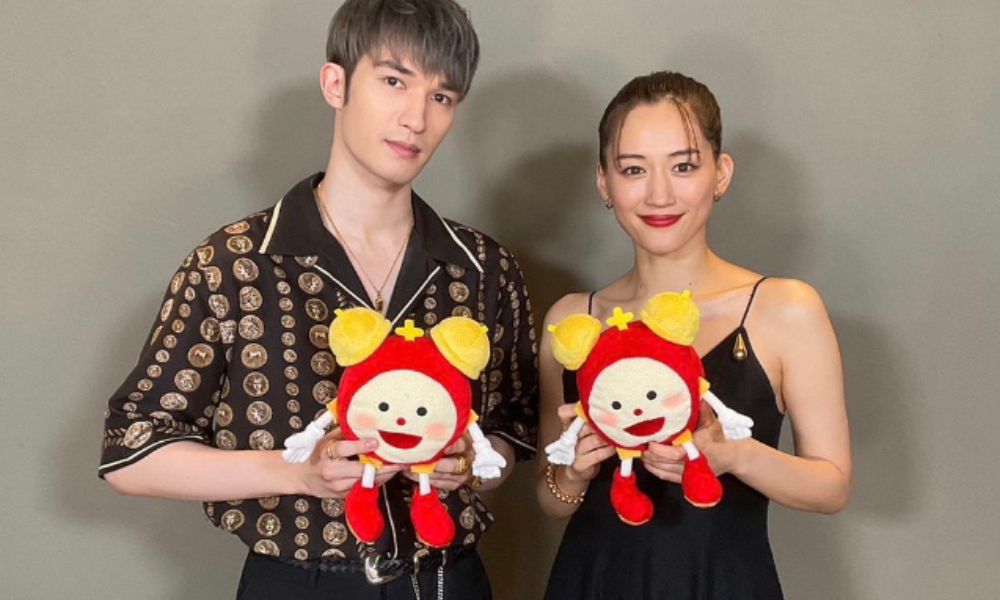 SixTONESのジェシー（左）と女優・綾瀬はるか（右）が赤いキャラクターのぬいぐるみを手に並んで微笑むツーショット写真